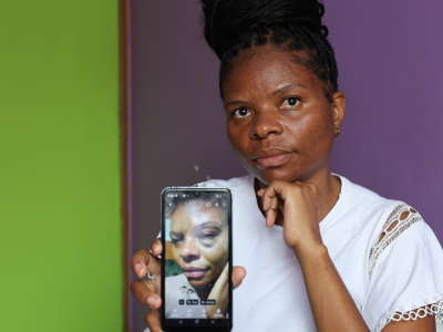 Ugandisk kvinde viser forslået billede af sig selv på telefonen