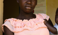 Kvinde i lyserød kjole i Uganda med barn på armen