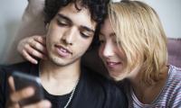 Ungt par læser om sexsygdomme på telefon